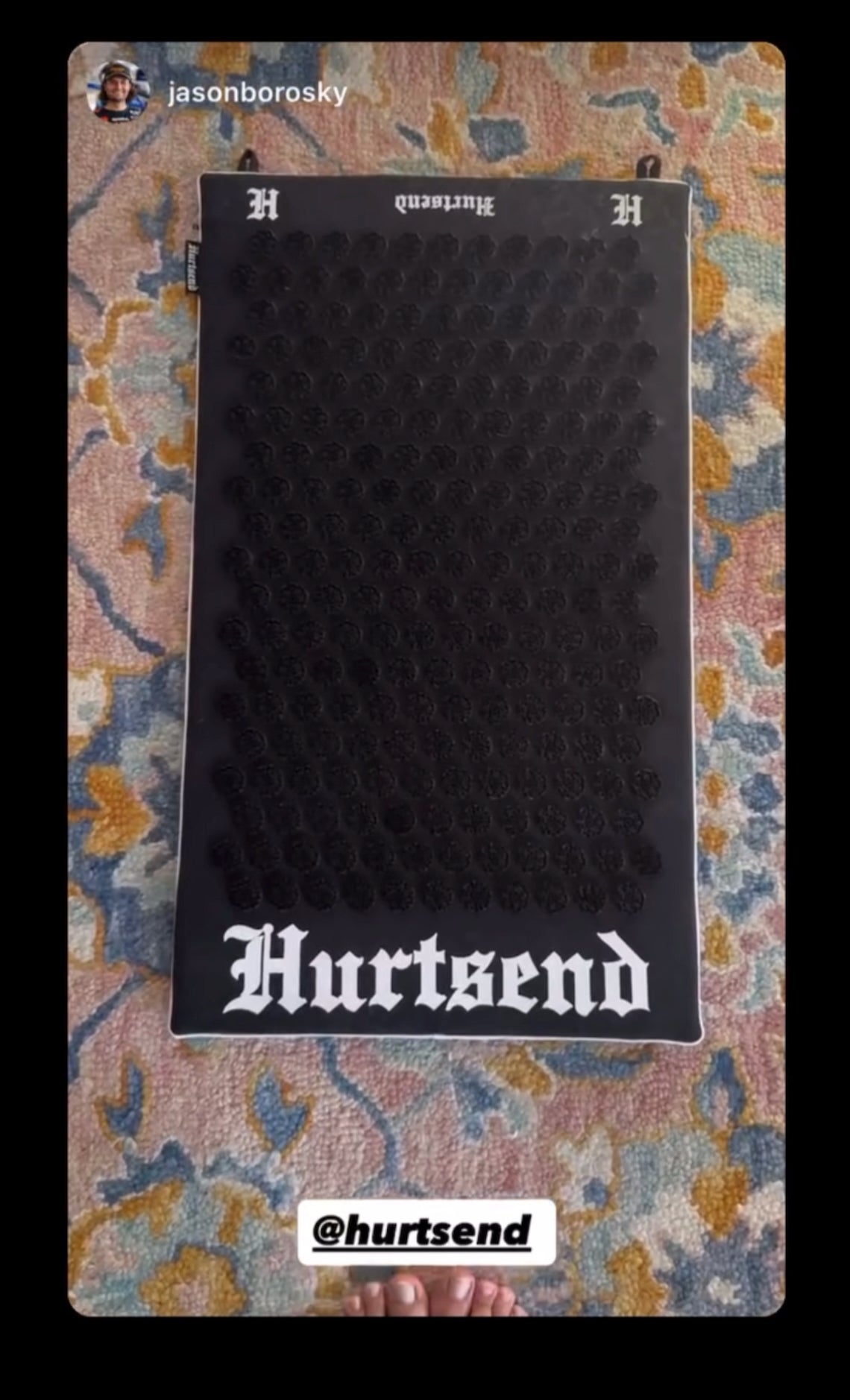 Black textured mat with 'Hurtsend' branding on a patterned fabric background